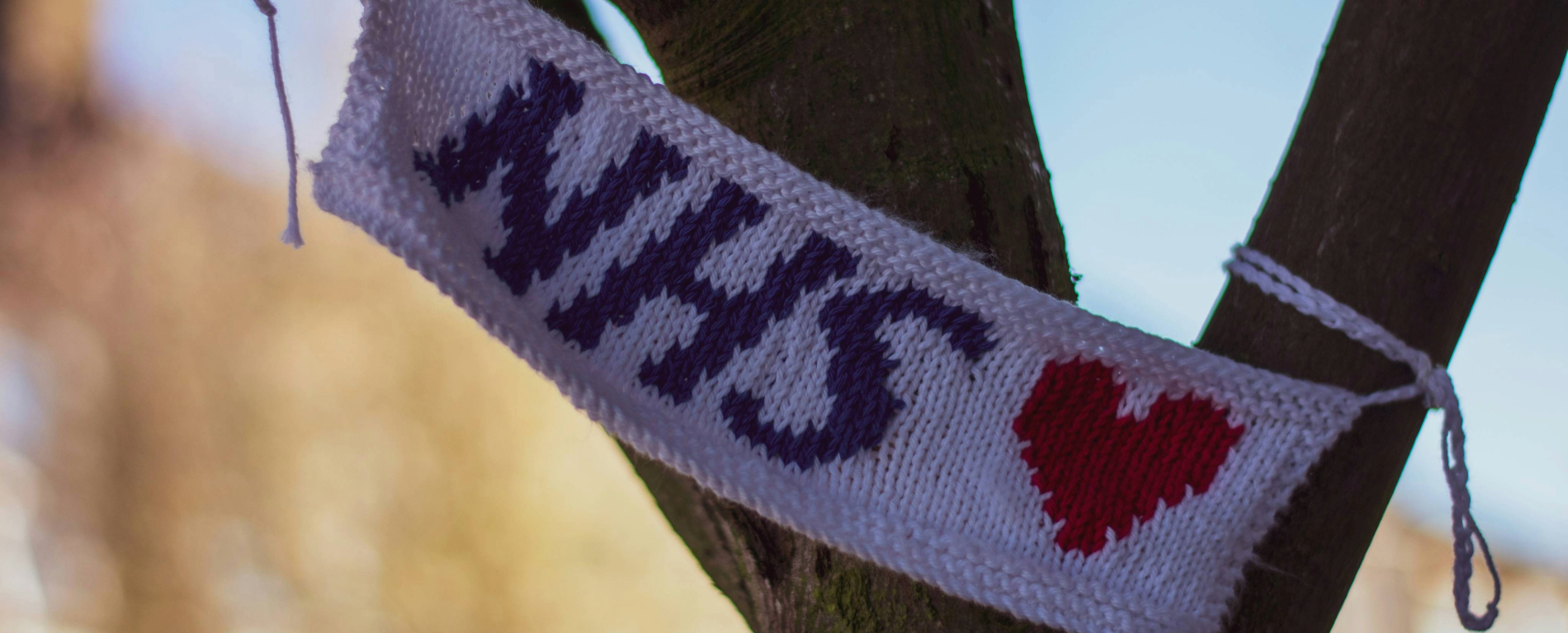 NHS knitted banner hanging from a tree