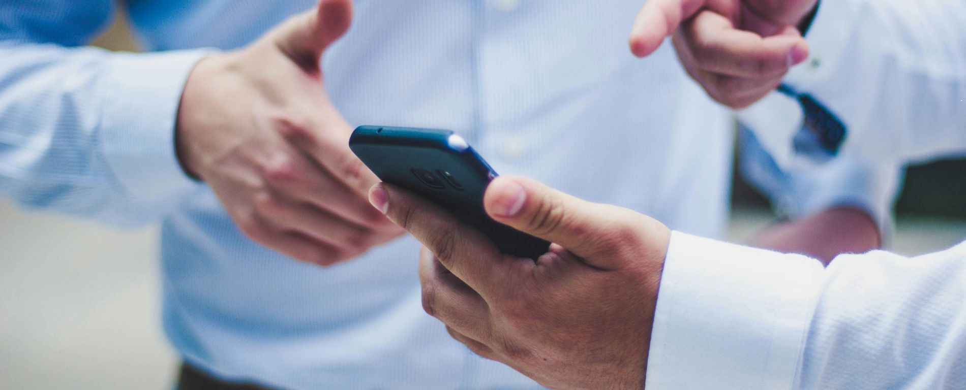 Two men in suits looking at a phone