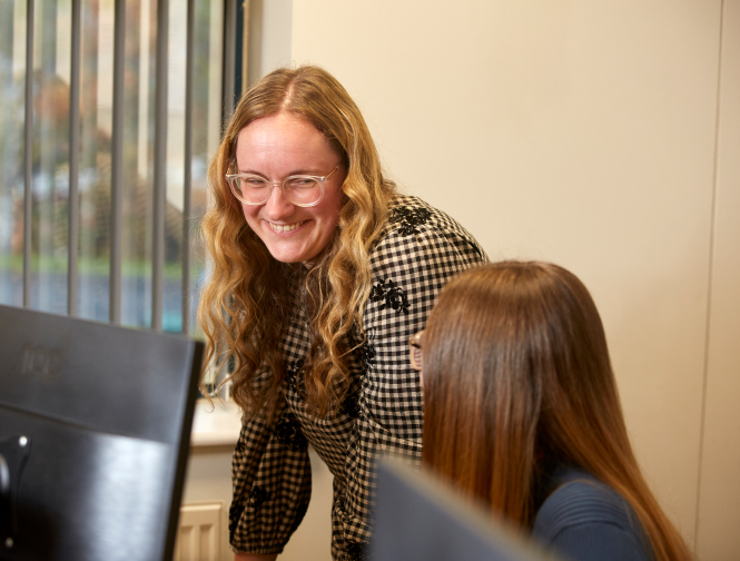Two colleagues discussing work at office desk