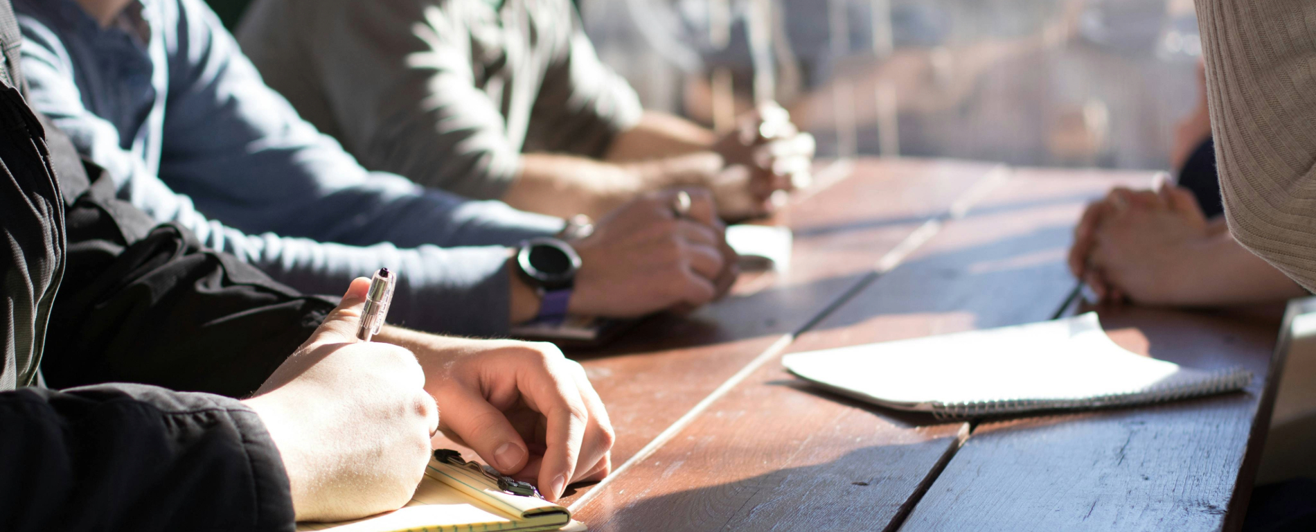hands and arms around a table in a work meeting