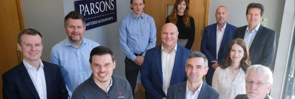 A selection of business people stood at the bottom of the stairs smiling at the camera