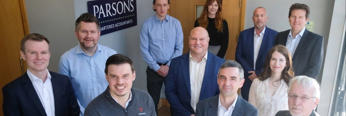 A selection of business people stood at the bottom of the stairs smiling at the camera