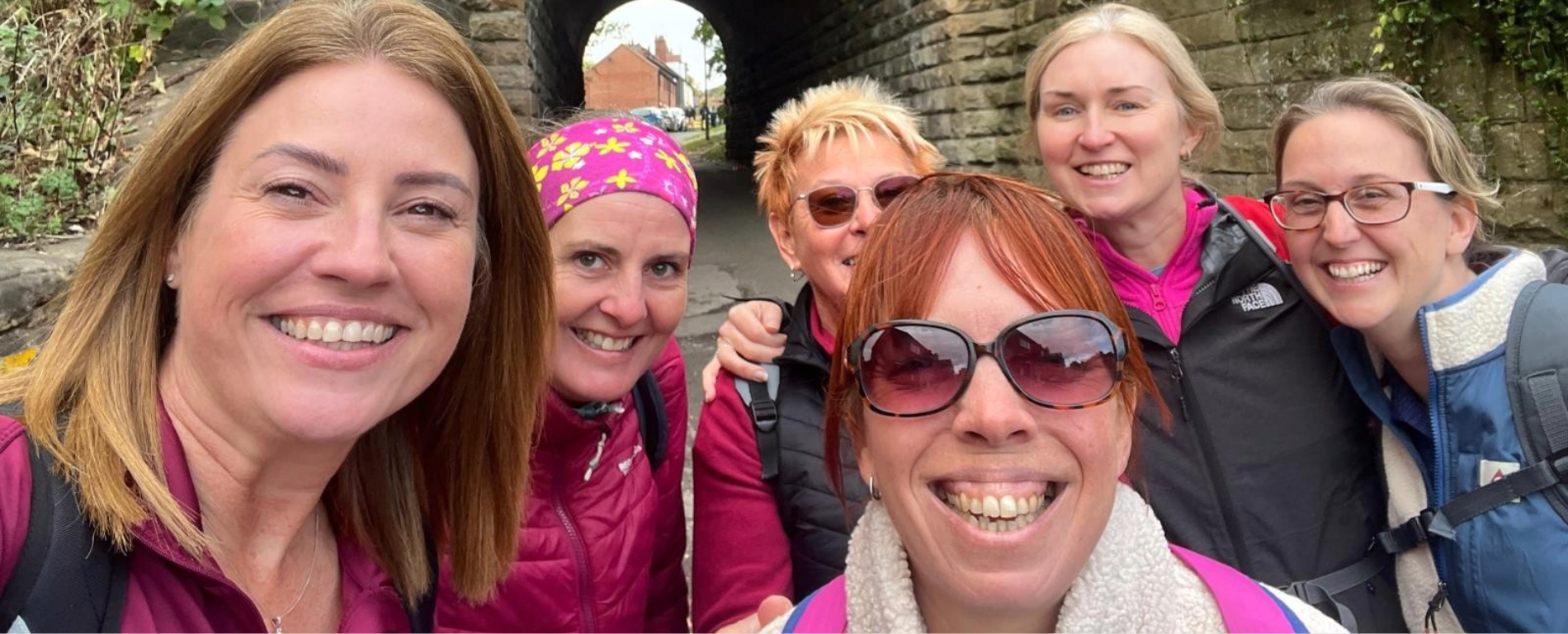 Group of women smiling as they take part in a sponsored walk for charity
